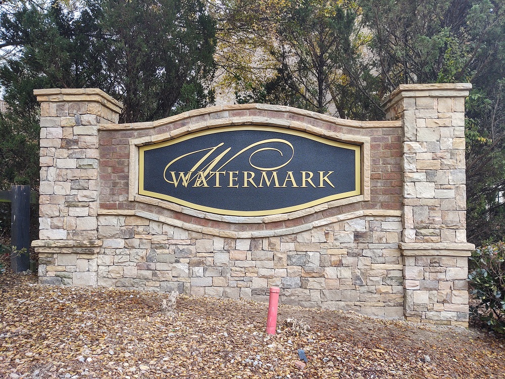 Watermark subdivision monument sign with stone columns, brick body, and gold accent frame