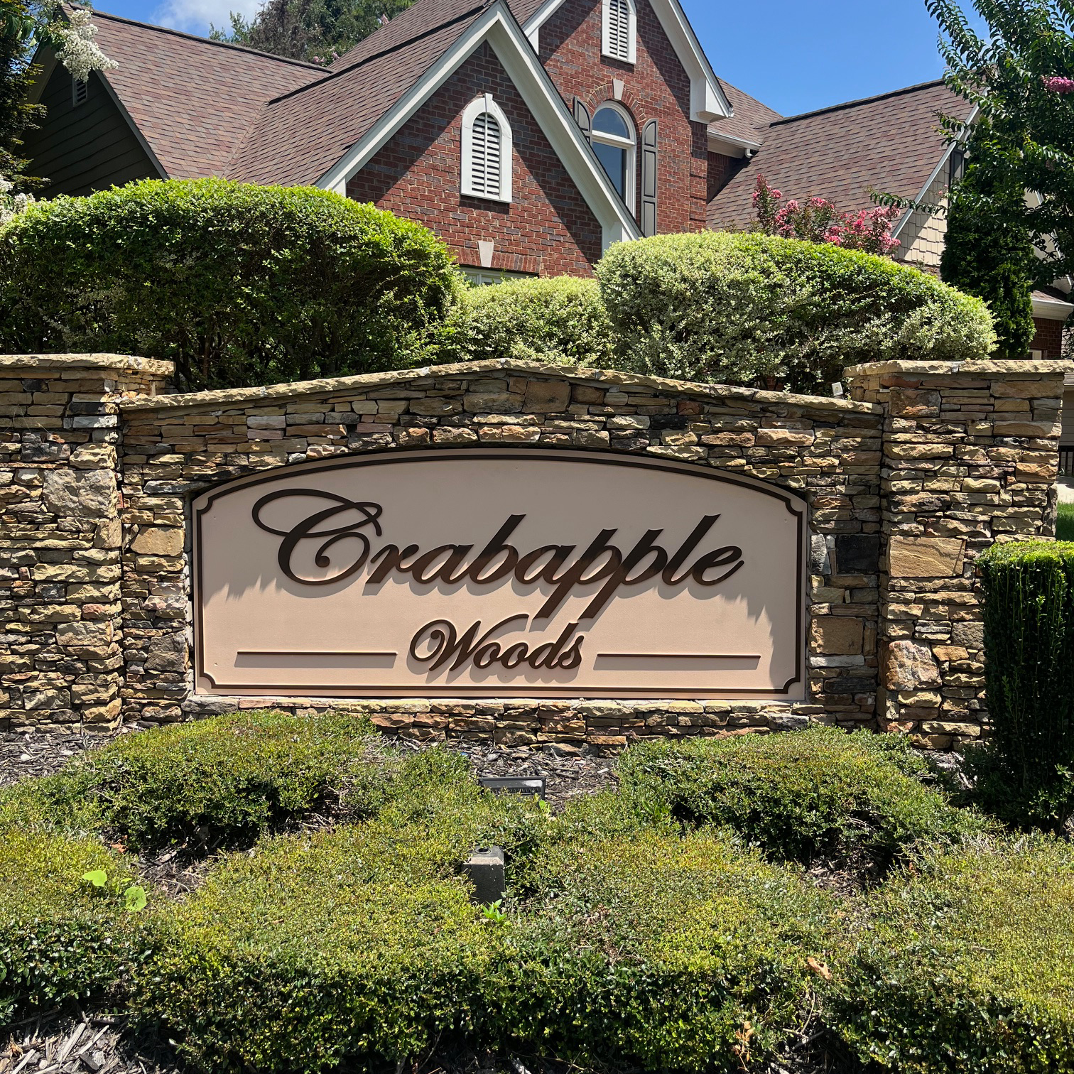 Stone monument entrance sign with Crabapple Woods community name in script lettering at a Milton Georgia neighborhood.