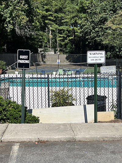 Guest parking and pool safety signs on black fence at a neighborhood swimming pool in a Georgia subdivision.
