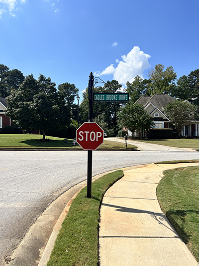 Ornamental black post with “Eagles Brooke Drive” street blade and STOP sign at HOA intersection in Locust Grove, Georgia.