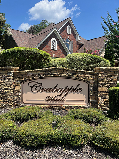 Stone monument entrance sign with Crabapple Woods community name in script lettering at a Milton Georgia neighborhood.