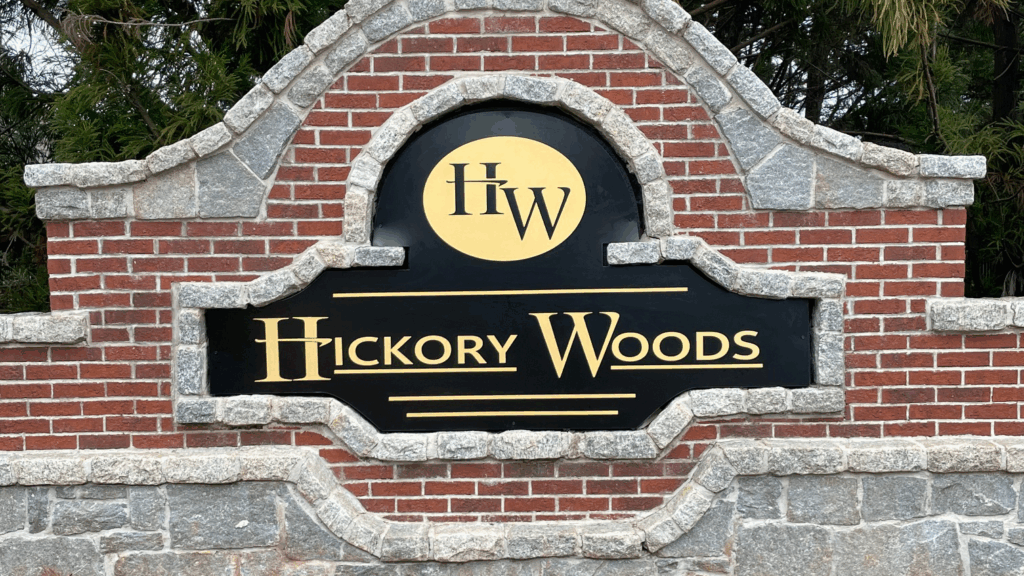 Hickory Woods neighborhood monument sign with gold text and brick masonry entryway in Marietta GA.