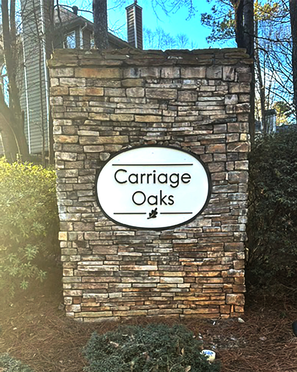 Carriage Oaks neighborhood entrance monument with stacked-stone pillar and vertical oval plaque, Marietta GA, Cobb County.