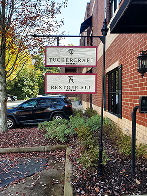 Subdivision sign for Tucker Craft and Restore All in Marietta, GA, displayed outside a brick building with autumn landscaping.