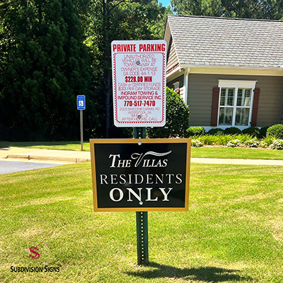 Residents only community sign for The Villas with black and gold panel mounted below parking enforcement signage in Dallas, GA.