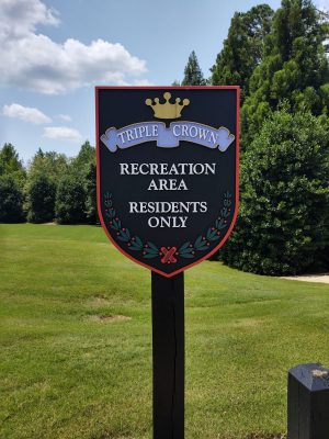 Triple Crown subdivision entrance sign with gold crown logo and residents only recreation area notice on shield-shaped monument sign