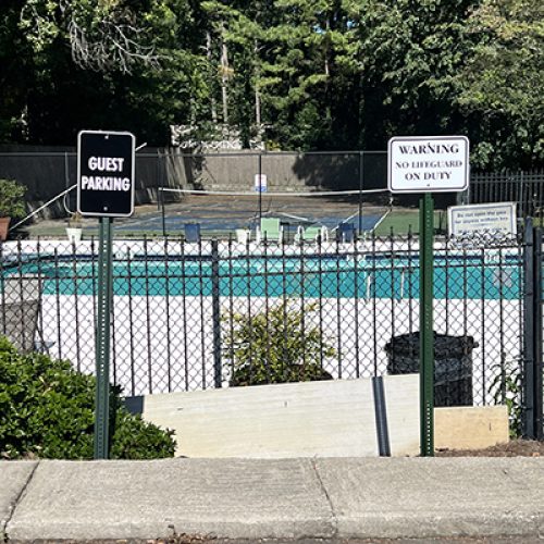 Guest parking and pool safety signs on black fence at a neighborhood swimming pool in a Georgia subdivision.