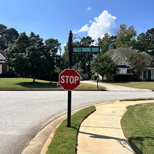 Ornamental black post with “Eagles Brooke Drive” street blade and STOP sign at HOA intersection in Locust Grove, Georgia.